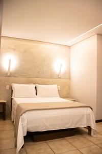 a bedroom with a large bed with two lights on the wall at Pousada Farol dos Borbas in Abraão