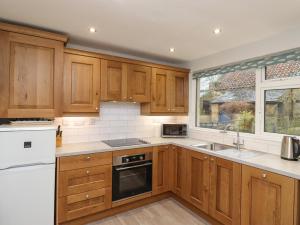 una cocina con armarios de madera y una ventana en Jasmine Cottage en Alnwick
