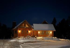 a log cabin with lights on in the snow at night at Lake Tower Lodge in New Rome