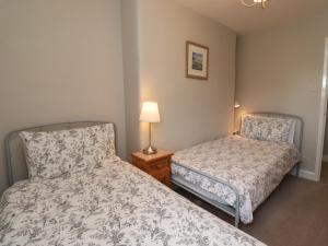 a bedroom with two beds and a lamp on a table at Jasmine Cottage in Alnwick