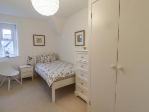 a bedroom with a bed and a dresser and a window at Rose Cottage in Alnwick