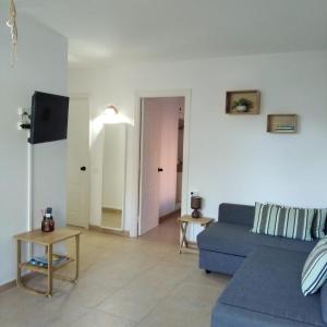 een woonkamer met een blauwe bank en een televisie bij Es Niuet in Cala Galdana