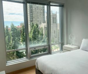 a bedroom with a large window with a view of a city at Spring Serene in Vancouver
