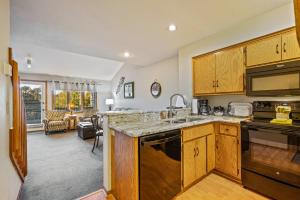 Evergreen Hill Condominiums في فيش كريك: مطبخ مع دواليب خشبية وغرفة معيشة