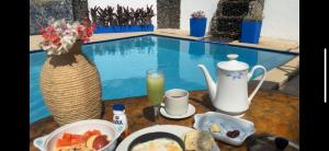 una mesa de desayuno con comida y un jarrón y una piscina en Tayrona Angel Lodge en El Zaino