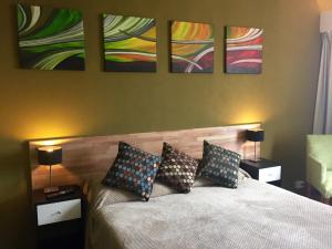 een slaapkamer met een bed met drie schilderijen aan de muur bij Center Suites Bariloche in Bariloche