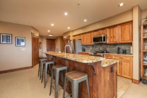 a large kitchen with wooden cabinets and bar stools at Crystal Peak Expedition Condo: Ski-In, Ski-Out Luxury in Breckenridge