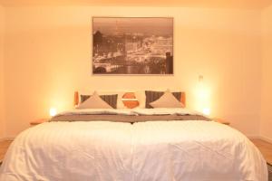 ein Schlafzimmer mit einem weißen Bett mit einem Gemälde darüber in der Unterkunft Ruhige Ferienwohnung im Grünen in Arnsberg