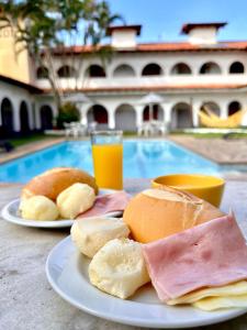 a plate of breakfast foods and a glass of orange juice at Pousada Puerta Del Sol Rio das Ostras in Rio das Ostras