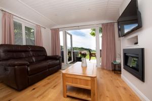 a living room with a leather couch and a television at Lomond View in Langbank