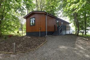 a small wooden cabin with a staircase in a yard at Lomond View in Langbank