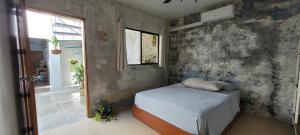 a bedroom with a bed and a concrete wall at The Stone Elephant - A place to relax in town with Hot Water and a Pool in San Juan del Sur