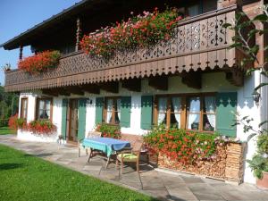 a house with a blue table and chairs and flowers at Landhaus Caesar - Hotel Garni in Bad Heilbrunn