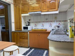 a kitchen with wooden cabinets and a sink at J & F Homestay - Abu Dhabi in Abu Dhabi