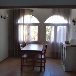 een eetkamer met een tafel en twee ramen bij Es Niuet in Cala Galdana