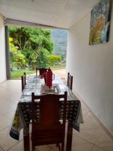 une table à manger avec des chaises, une table et une fenêtre dans l'établissement Encanto da Montanha Hospedagem, à Príncipe