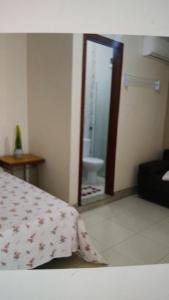 ein Schlafzimmer mit einem Bett und ein Badezimmer mit einem Spiegel in der Unterkunft Casa de Praia in Fundão