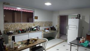 eine Küche mit einem weißen Kühlschrank und einem Tisch in der Unterkunft Casa de Praia in Fundão
