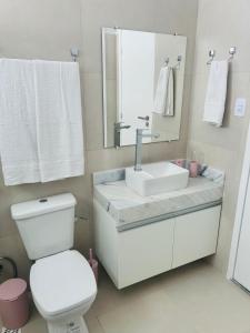 a bathroom with a toilet and a sink and a mirror at Atena Flats in Aracaju