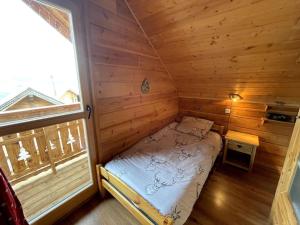 een kleine slaapkamer met een bed in een blokhut bij Chalet Mon Etoile - La Joue du Loup in Le Dévoluy