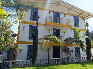 a yellow and white building with blue windows and palm trees at Hotel sol del lago in Guatapé