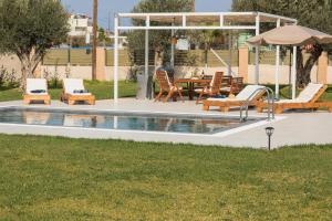 uma piscina com cadeiras, uma mesa e um guarda-sol em Villa Cervus Dianae em Kallithea Rhodes