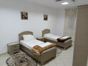 2 camas en una habitación con paredes blancas en IMMEUBLE BRINI en Kairouan