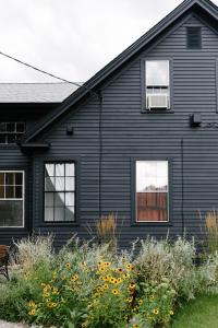 Eileen of Mystic في ميستيك: منزل أسود مع نوافذ وزهور في الفناء