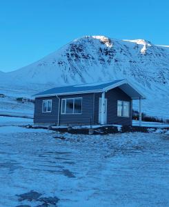 uma pequena casa em frente a uma montanha coberta de neve em Tungukot sumarhús em Akureyri