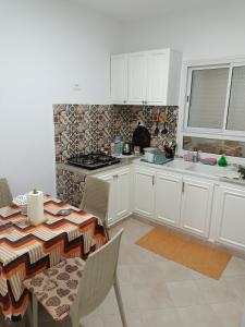 una cocina con armarios blancos y una mesa con sillas. en IMMEUBLE BRINI en Kairouan