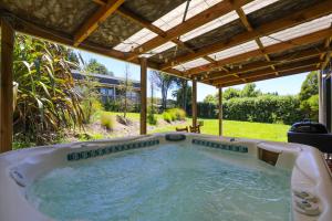 a hot tub in a backyard with a pergola at Kereru Rest in Rotorua