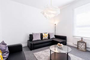 a living room with a black couch and a glass table at The Urban Apartment in Doncaster
