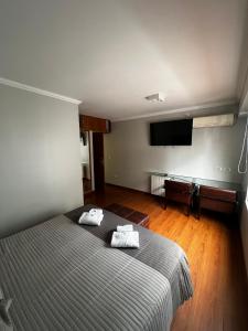 um quarto com uma cama e uma televisão de ecrã plano em Goya Hotel em Buenos Aires