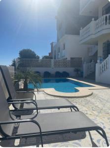 a pair of chairs sitting next to a swimming pool at Villa Flores Mijas Fuengirola in Santa Fe de los Boliches
