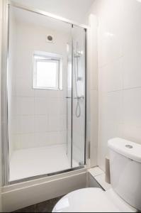 a white bathroom with a shower and a toilet at Hatton Homes - Thackeray Avenue in London