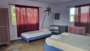 a room with two beds and a desk and a table at Il Triangolo Hostel in Las Galeras
