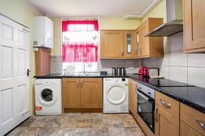 a kitchen with a washing machine and a window at Hatton Homes - Thackeray Avenue in London