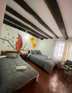 dwa łóżka w pokoju z malowidłem ściennym w obiekcie Beija Flor Hostel w mieście Villa de Leyva