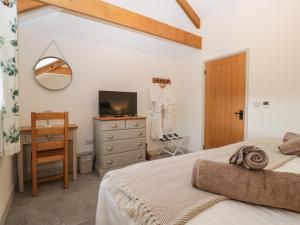 a bedroom with a bed and a desk and a television at The Byre in Bridgend