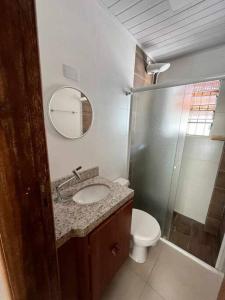 a bathroom with a sink and a toilet and a mirror at Condomínio Costa Azul in Caraguatatuba