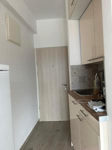 uma pequena cozinha com armários brancos e uma porta em Natali 3 em Sutomore