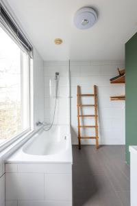 a bathroom with a bath tub and a window at Bed zonder Breakfast in Amsterdam