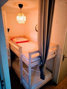 Cette petite chambre comprend un lit superposé avec un rideau. dans l'établissement Studio Cabine Piscine-Clim-Parking-Plage200m, à Valras-Plage