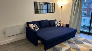 a blue couch in a living room with a window at Hemel Hives in Hemel Hempstead