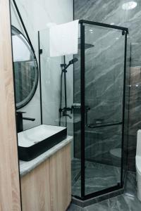 a bathroom with a shower with a sink and a mirror at Sunrise Hotel in Taldykorgan