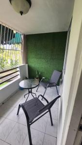 d'un balcon avec deux chaises, une table et un mur vert. dans l'établissement Acogedor Apartamento Completo 2 Recamaras 2 Baños., à Panama City