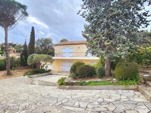 une grande maison jaune avec des arbres et une allée en pierre dans l'établissement Villa La Chenal, à Fréjus
