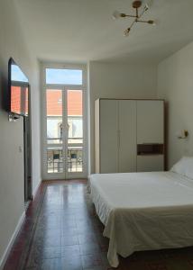 a bedroom with a white bed and a large window at Noliday Savona Center Art Deco Apartment in Savona
