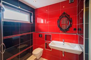 czerwona łazienka z umywalką i toaletą w obiekcie Apartament na poddaszu w mieście Zduńska Wola