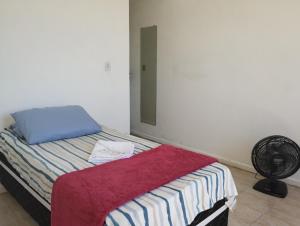 1 dormitorio con 1 cama con almohada y ventilador en Pousada Jardins Campista, en Macaé